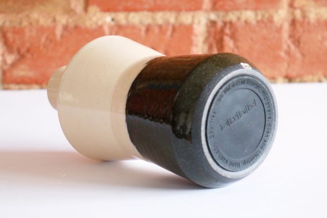 The bottom of a bottle with a shallow clay foot ring that hides a non-slip rubber sticker.
