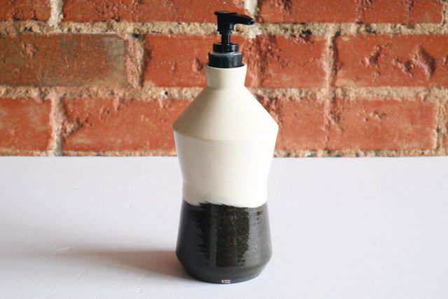 Bottle with a cinched waist with clean angles. Black clay at the base comes nearly to the waist, just below center, then transitions to white clay for the top half. The transition is a hard edge, but forms a an organic line around the piece.
