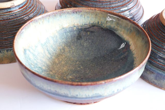 The inside of one bowl, with a red-brown rim and halo of flowing whites & blues even more eye-like surrounding the deeper blue-brown pupil of the rounded inner bowl -- smooth and hemispheric.
