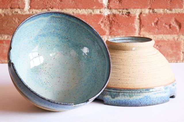 One bowl facing out, revealing the inside glaze, resting against the other inverted bowl.
