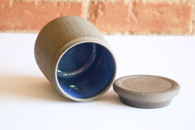 The walls of the jar have a slight rhythmic chattering that's visible when it catches the light. The lid is slab-like, with a beveled outer ring and inset top, and underneath it a locating flange that sticks into the jar about a half inch.
