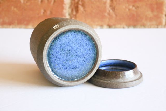 The underside has a similar beveled outer ring and inset base, revealing a blue speckled glaze that flares towards green at the outside. The inside of the lid has the same glaze hidden away.
