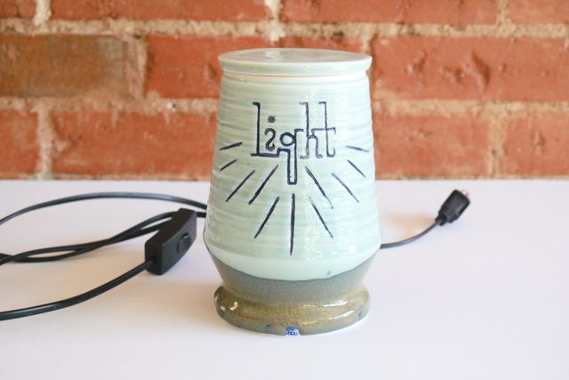 With the light off, most of the jar is a soft aqua blue, with the text and rays in darker blue, and the base a green with specks of gold. The base angles in then back out, and in again slowly towards the lid - almost like a lava lamp.
