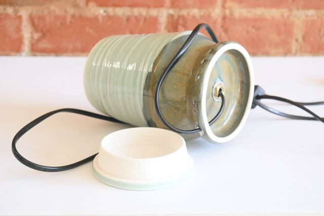 The base is a hollow foot ring with a hole in the back, where the black lamp cord passes into the foot, and then through a hole in the center of the piece where the light socket is mounted.
