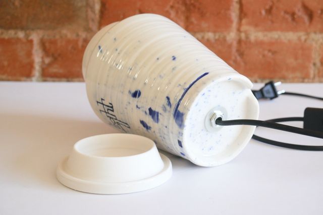 The lid is removed, and has a tall locating flange. The jar is on it's side, showing a hollow foot ring at the base, where the power cable emerges from the bulb socket mount, and passes through a notch in the back of the foot.
