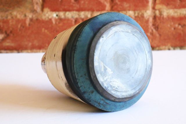 The oxidized copper is almost iridescent near the base, though it has a matte finish. The walls cut in sharply to an angular foot ring, and the actual underside has turned black.