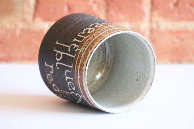 The inside and rim are glazed white, with organic patches of warm brown where the clay shows through.

