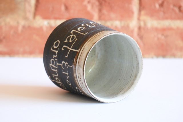 The inside and rim are glazed white, with organic patches of warm brown where the clay shows through.
