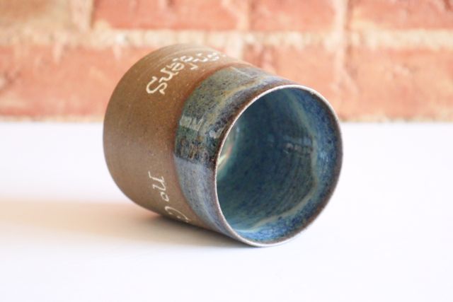 The rim and inside have an organic floating blue glaze with specks of white and green dipped at an angle.
